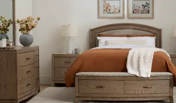 Neutral-toned bedroom with wooden bed, dresser, two nightstands, and orange bedding