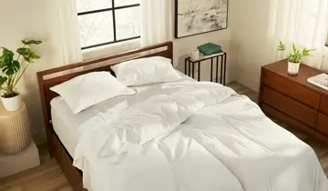 Bright bedroom with a wooden bed, white bedding, nightstand, and dresser