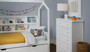 Child's bedroom featuring a white house bed, bookshelf headboard, and tall dresser