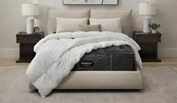 A bedroom with a bed, dark mattress, white comforter, and two nightstands