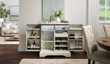 Open white bar cabinet with drinks and glassware between dining and living rooms