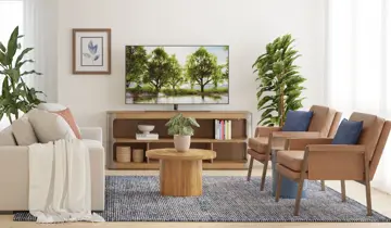 Living room with white sofa, two brown armchairs, wooden coffee table, TV stand, and plants