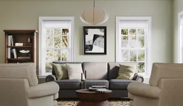 Light green living room with gray sofa, armchairs, coffee table, and bookshelf