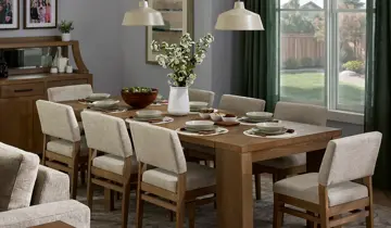 Warm dining room with a wooden table, eight cream upholstered chairs, buffet, and dark green window drapes