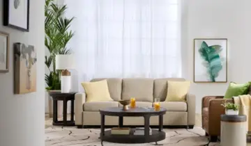 Bright living room with beige sofa, round coffee table, and brown armchair on a patterned rug