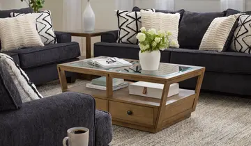 Cozy living room with dark gray upholstered sofas, a wooden glass-top coffee table, and a light rug