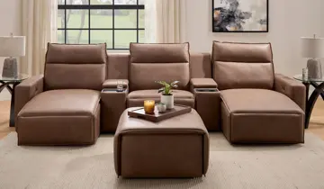 Brown leather reclining sectional sofa, chaises, console tables, and ottoman in a living room