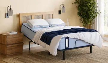 Light-filled bedroom showcases an adjustable bed with a blue mattress, white bedding, wood headboard, and nightstand