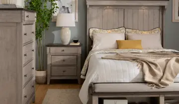 Cozy bedroom with light gray wood bed, matching nightstand and dresser, white bedding, and soft lighting