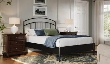Bedroom with black metal bed, white bedding, dark wood nightstands, and patterned rug