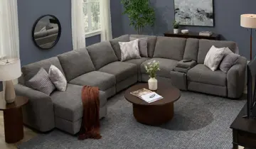 Inviting living room features a large gray U-shaped modular sectional, round coffee table, and layered textures