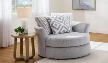 Gray round swivel chair, wooden table with lamp and plant in bright room