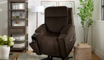 Warm living room with a plush brown recliner, wood shelf, floor lamp, and leafy plant