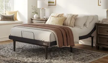Bedroom with an adjustable bed, two nightstands, a rug, and a window seat