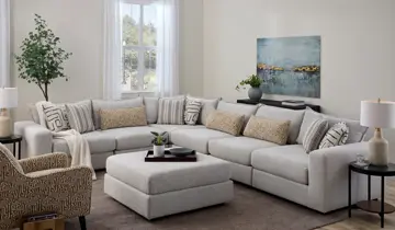 Living room with a large light gray sectional sofa, ottoman, and accent chair