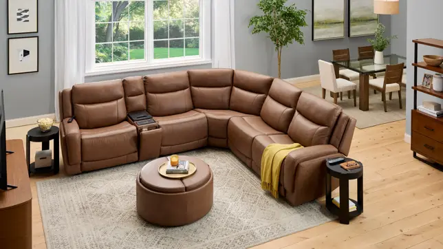 Comfortable brown leather reclining sectional and ottoman in a spacious open-concept living and dining area