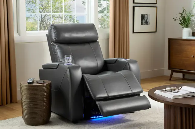 Modern living room with a reclined gray chair, blue underlighting, side table, window, and wood cabinet