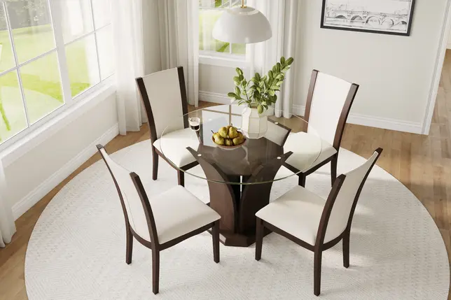 Dining room with a round glass table, dark wood base, four cream chairs, white rug, and large bright windows