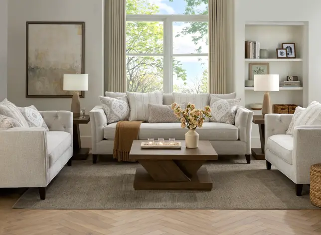 Bright living room with light gray upholstered seating, dark wood tables, and neutral decor