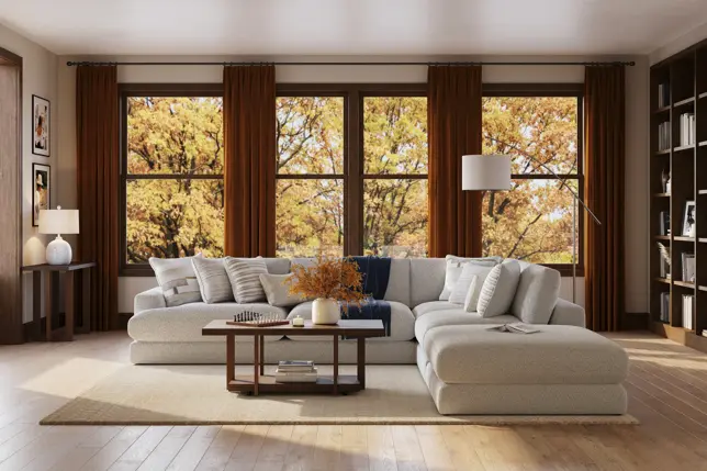 Spacious living room featuring a light sectional sofa, dark wood furniture, and warm autumn views through large windows