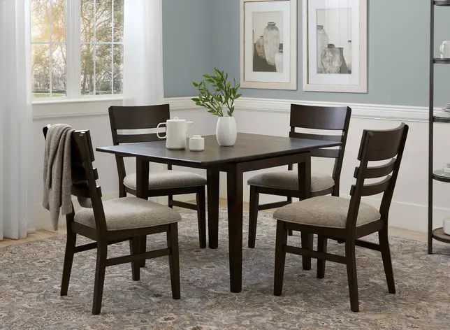Bright dining room with a dark wood table, four upholstered chairs, light blue walls, and a patterned rug