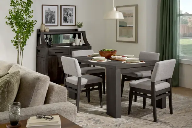Open dining and living area featuring a dark gray dining set, light gray upholstered chairs, and a sofa