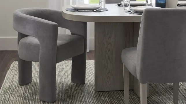 Modern dining room featuring gray upholstered chairs, a light wood oval table, and a textured rug