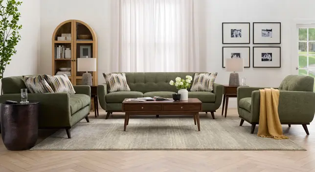 Living room with olive green sofa and armchairs, dark wood coffee table, light rug, and arched cabinet