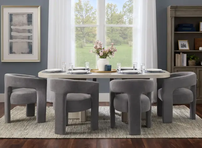 Dining room with an oval table, four upholstered gray chairs, a window, and bookshelf