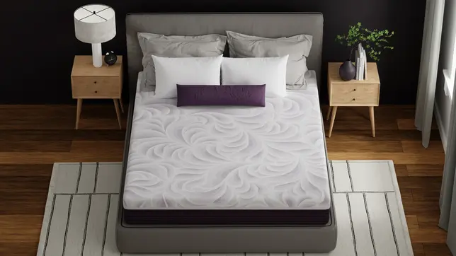 Modern bedroom with a gray bed, white swirl-patterned mattress, purple accent pillow, wood nightstands, and a striped rug