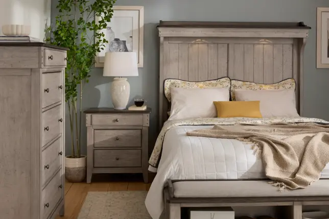 Cozy bedroom with light gray distressed wood furniture, blue walls, a bed, nightstand, and dresser