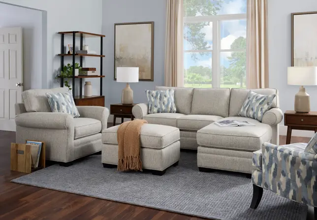 Light-filled living room with beige sectional, armchair, ottoman, and accent chair