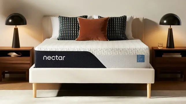 Bedroom with a white mattress on a cream bed frame, two nightstands, and lamps