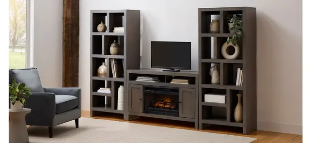 Gray media console with asymmetrical cubby shelves, fireplace, and TV, beside an armchair in a bright living room