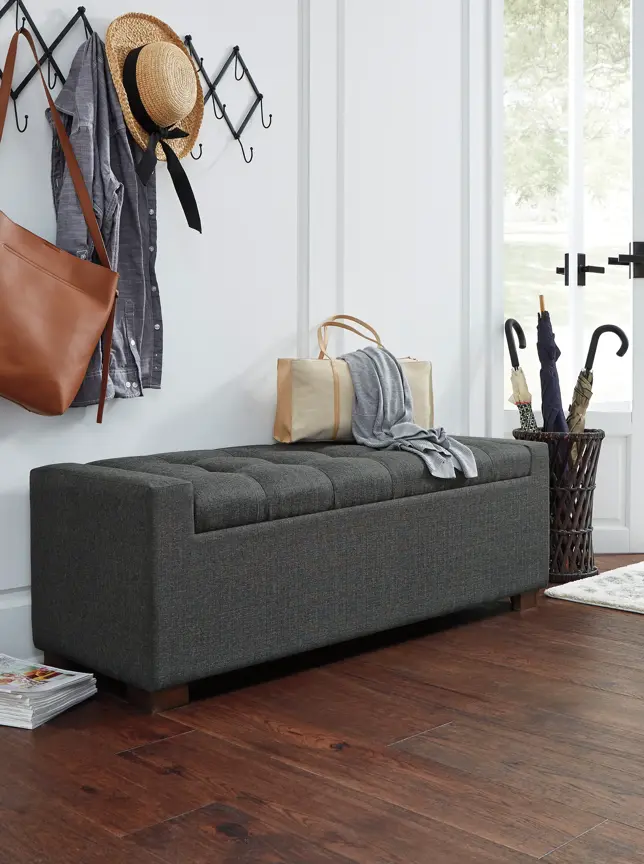 Entryway with a dark gray tufted storage bench, coat rack, and umbrella stand on dark wood floors