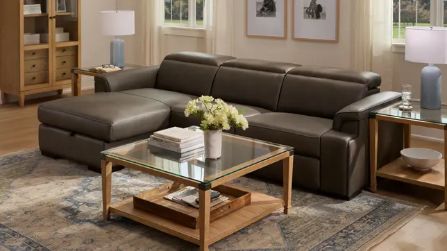 Bright living room with a gray leather sectional, glass and wood tables, blue lamps, and a patterned rug